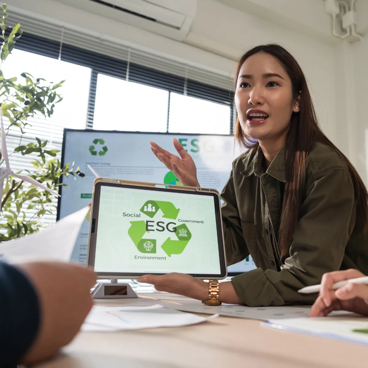 An American-Asian woman explains ESG using a presentation on a tablet computer