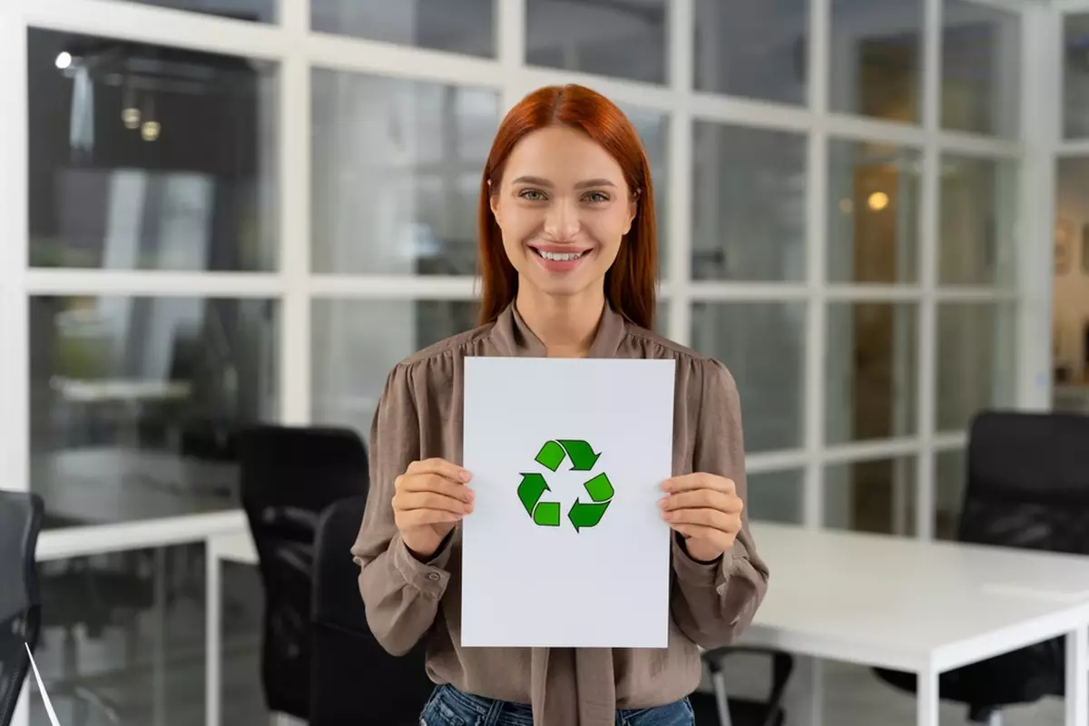Smiling woman holding recycling sign